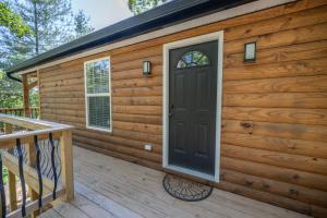 a wooden cabin with a door on a deck at Alone At Last - New LUX Tiny Cabin - WiFi - Hot Tub 5321 in Rogers