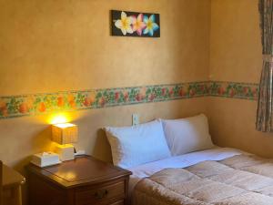 a bedroom with a bed and a table with a lamp at Miles Town in Ito