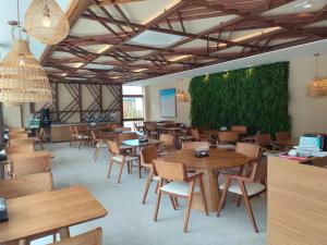 a restaurant with tables and chairs and a green wall at Studio Confortável em Muro Alto in Ipojuca