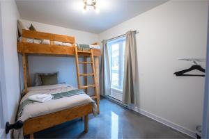 a bedroom with a bunk bed and a window at La Kobber Hüs - Élégance au coeur de la ville in Murdochville