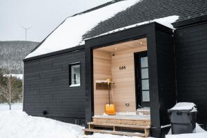 a black house with a black roof in the snow at La Kobber Hüs - Élégance au coeur de la ville in Murdochville