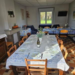 a dining room with a long table with plates and wine glasses at Gîtes de la terrette in Tribehou