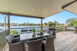 an outdoor deck with a table and chairs and a grill at Acacia Shores - Waterfront in Yamba