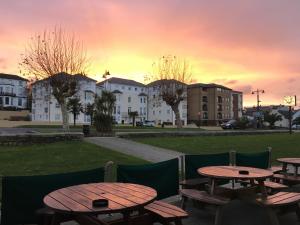 a group of picnic tables with a sunset in the background at Dog Friendly Apartment with Sea Views in Ryde