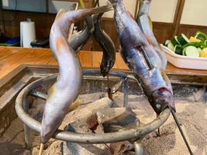 three fish being cooked on a stove at 畑のおやど in Asago
