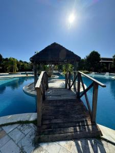 eine Holzbrücke mit einer Hütte auf einem Pool in der Unterkunft Studio Iloa Vista Piscina 004V in Barra de São Miguel