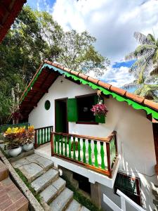 een klein huis met een groen en wit bij Chalé Colonial Aconchegante a 5 Min do Centro in Nova Friburgo