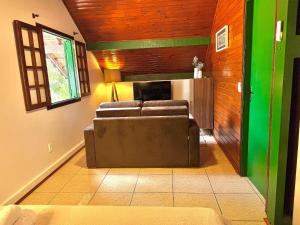 een woonkamer met een bank en een televisie bij Chalé Colonial Aconchegante a 5 Min do Centro in Nova Friburgo