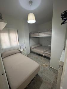 a small bedroom with a bed and a lamp at Apartamento Sol y Playa in Rota +5 photos