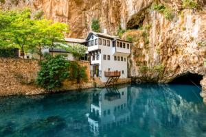 a house sitting in the middle of a body of water at Villa Mostar - Resort Rozic in Mostar