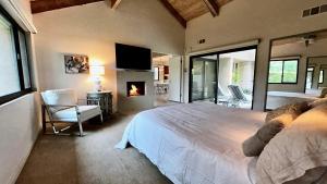 a bedroom with a large white bed and a fireplace at Courtside Contemporary in Rancho Mirage