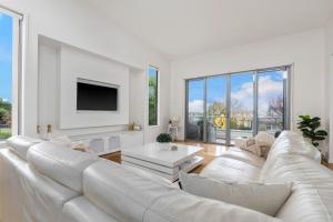 a white living room with a white couch and a tv at Grandview on Bayview in Inverloch