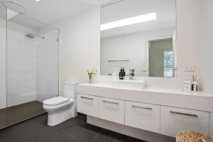 a white bathroom with a toilet and a sink at Grandview on Bayview in Inverloch +20 photos