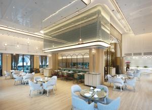 a restaurant with white chairs and tables and a cafeteria at Sanya Golden Phoenix Seaview Hotel in Sanya