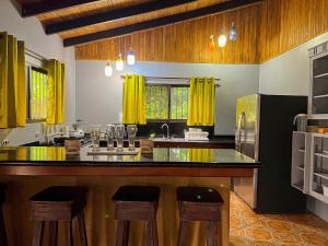 a kitchen with a counter and some yellow curtains at La Casa de Piedra in Puerto Jiménez