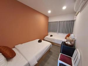 a small room with two beds and a table at Nomads Homestay Sriracha in Chon Buri