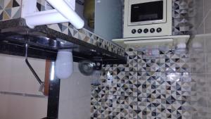 a kitchen with a sink and a microwave at Cantinho da Sagrada família in São Pedro da Aldeia +3 photos
