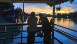two women sitting at a bar looking at the water at souksanh River Bungalow in Along