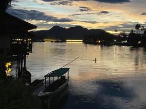 a boat on a river with a person on a pole at souksanh River Bungalow in Along