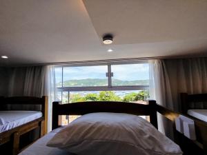 阿拉亚尔-杜卡布Hostel Casa da Pedra的一间带床和大窗户的卧室