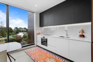 Una cocina con gabinetes blancos y una ventana grande. en 1BR with Balcony Close to Ferry by Zodiak Stays, en Auckland