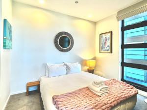 Un dormitorio con una cama y un espejo en la pared. en 1BR with Balcony Close to Ferry by Zodiak Stays, en Auckland