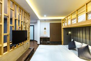 a bedroom with a bed with a tv and shelves at The G Hotel Hue in Hue