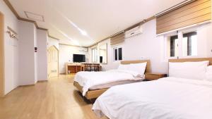 een slaapkamer met twee bedden en een televisie bij Sokcho Pine View Hotel in Sokcho