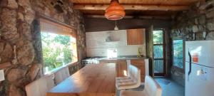 a kitchen with a wooden table and a stone wall at FUJI - Casas para relajar in Villa de Las Rosas