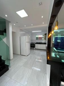 a kitchen with a refrigerator and a counter top at Casa Ferry Piscina Privativa e Hidro 300m da Praia in Praia Grande