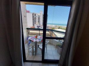 a room with a balcony with a table and a view at Lindo apto com vista mar, 200 mts da praia in Praia Grande