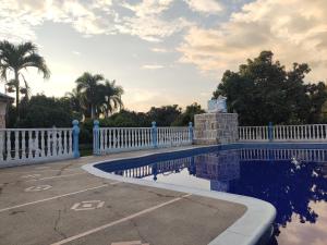 a swimming pool with a white fence and palm trees at Cabañas El Itali in Fusagasuga