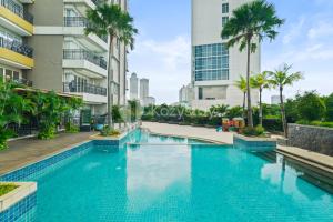 einem Pool in der Mitte eines Gebäudes mit Palmen in der Unterkunft Tovia by Kozystay - Senayan in Jakarta
