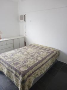 a bedroom with a bed and a white wall at Apartamento Guarujá - Praia Enseada in Guarujá