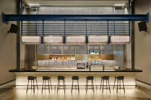 a bar in a restaurant with stools around it at Aloft by Marriott Bangkok Sukhumvit 11 in Bangkok