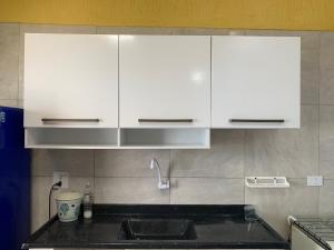 a kitchen with white cabinets and a sink at Aconchego Bertioga in Bertioga +19 photos