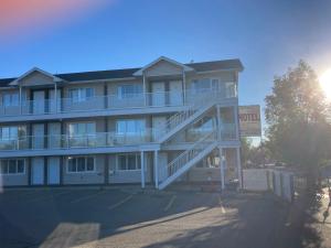 a large apartment building with a staircase in front of it at Raccoon Lodge Motel in Sylvan Lake