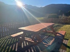 a wooden picnic table with the sun shining on it at Wohl eingerichtete Wohnung mit eigenem Balkon in Sankt Michael im Lungau