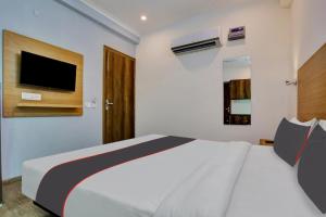 a bedroom with a bed and a tv on the wall at Collection O The Miscue in Gurgaon +23 photos