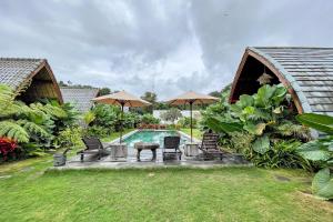 a backyard with a pool and chairs and umbrellas at The Caldera Villas in Kubupenlokan