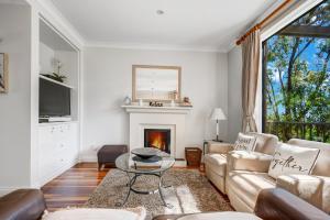 ein Wohnzimmer mit Couch und Kamin in der Unterkunft Villa Piccola Casa, Premier 2 Storey Villa, 2 Bedrooms, both with private ensuites, with third toilet on the ground floor in Pokolbin