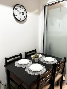 a black table with four chairs and a clock on the wall at Azure Staycation by Casa Lepap in Manila