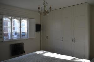 a bedroom with white cabinets and a bed with a window at Timeless high street hideaway in Hurstpierpoint