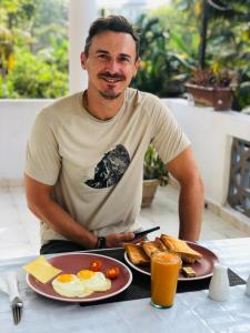 a man sitting at a table with eggs and toast at Villa Dream D in Hikkaduwa