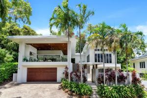a white house with palm trees in the background at Belle Escapes Canopy Heights in Palm Cove