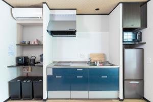a kitchen with blue cabinets and a stainless steel refrigerator at Ukiyoan Takasago in Tokyo