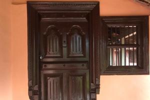a black door with a window on a wall at Athithi Homestay by StayApart in Avathi