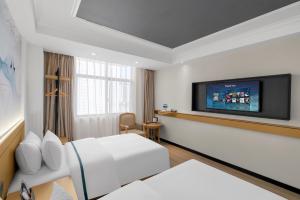 昆明Junao Hotel Nanping Pedestrian Street Branch的一间配有床和平板电视的酒店房间