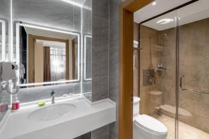昆明Junao Hotel Nanping Pedestrian Street Branch的带水槽、马桶和镜子的浴室
