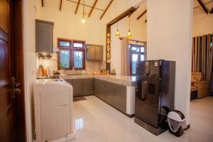 a large kitchen with a refrigerator and a sink at Sunset View Galle in Pedinnoruwa